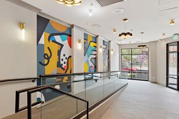 A large colorful painting hangs on the wall at the top of a staircase in a building